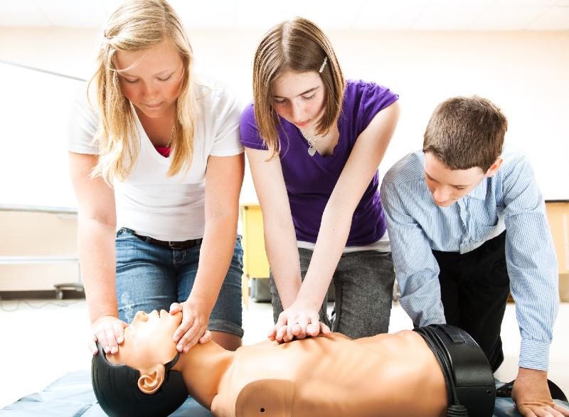 Students practicing CPR life saving techniques on a mannequin-first aid kits