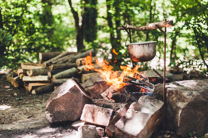 The pot is burning near the tent in the forest at night | what to pack in an emergency bag