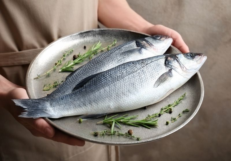 Woman holding metal dish with fresh fish How to fillet a fish SS