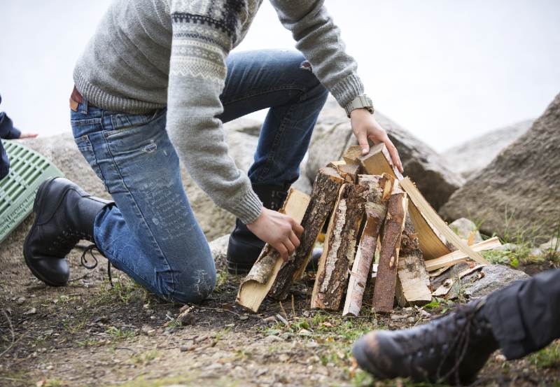 Man Arranging Firewood For Bonfire On Lakeside Camping-campfire