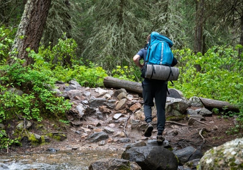 Man walking on rocky terrain | Tips to Help You Camp in the Rain