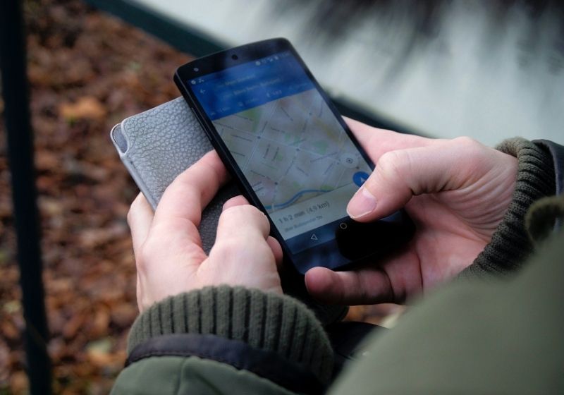 Person using google maps application through black Car camping essentials PX