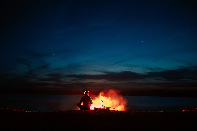 Silhouette of tourist around campfire at night on the river shore-Camping Without Electricity