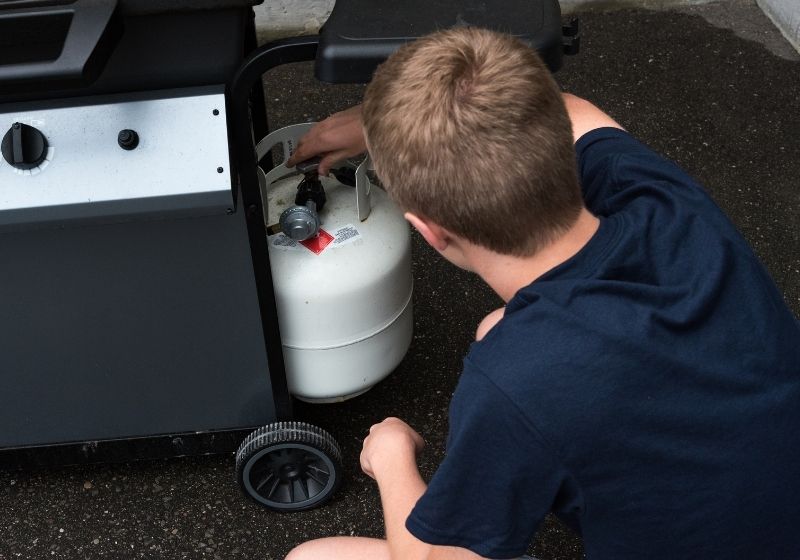 Teenager opening a propane tank for a barbecue Must have survival items SS
