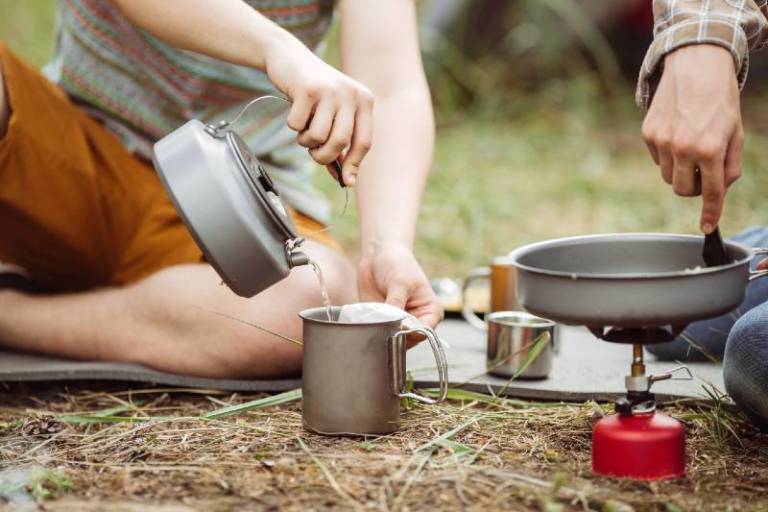 Two fellow campers making tea and preparing food in the forest Car camping essentials SS