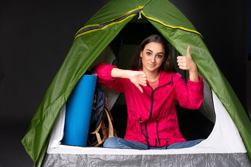 Young caucasian woman inside a camping green tent making good-bad sign | best camping tents