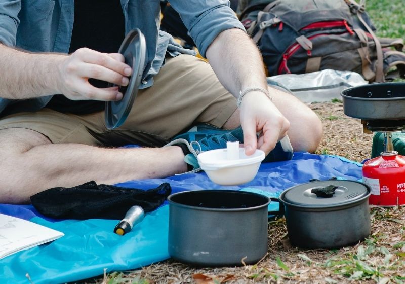 Young man preparing food during picnic after hiking Car camping essentials PX