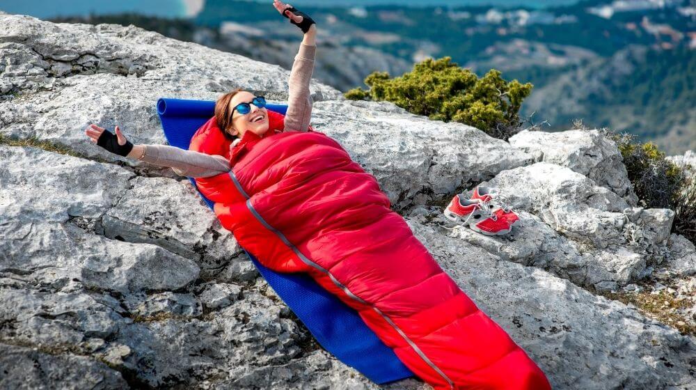 Young woman waking up in red sleeping bag | Best or Top Sleeping Bags for Hiking, Camping, Backpacking | Featured
