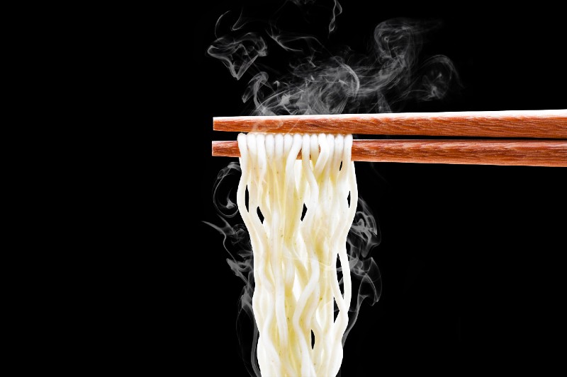 chopsticks noodles with smoke isolated on black background with clipping path-camping food hacks
