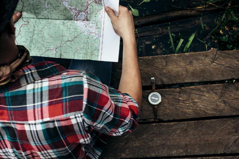 stylish hipster traveler exploring map at sunny forest and lake in the mountains-Camping Without Electricity
