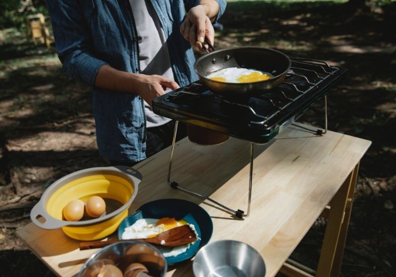 unrecognizable man frying eggs in camping Car camping essentials PX