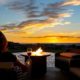 A woman relaxes with a glass of wine at night in front of an outdoor firepit on a patio of a luxury home | Top Reasons to Have a Firepit | featured