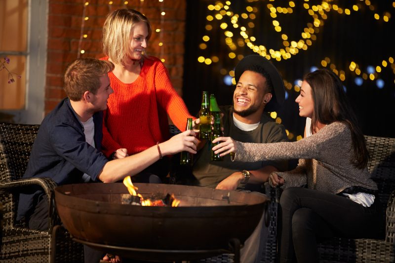 Group Of Friends Enjoying Evening Drinks By Firepit-firepit