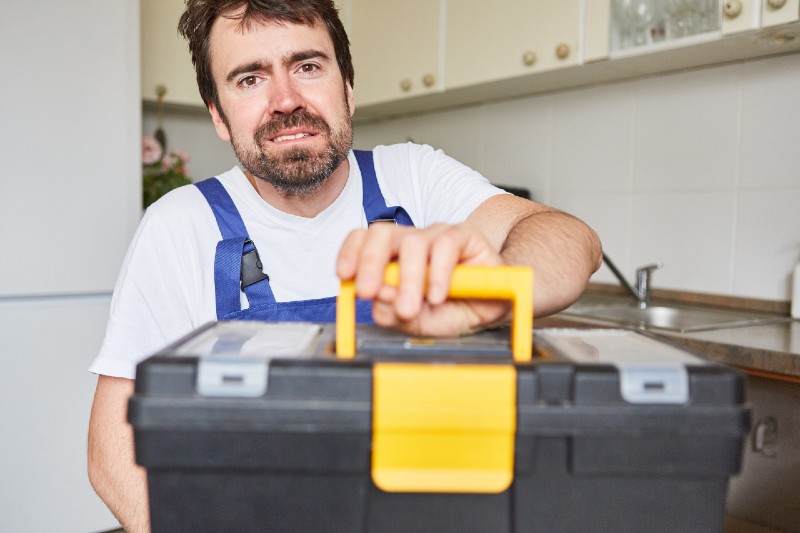 Man as a craftsman buying items from the plumber's emergency service with tool box in the kitchen