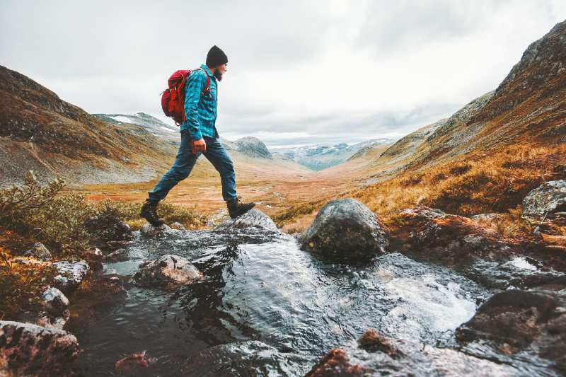 Man solo traveling backpacker hiking in scandinavian mountains-Camping Alone