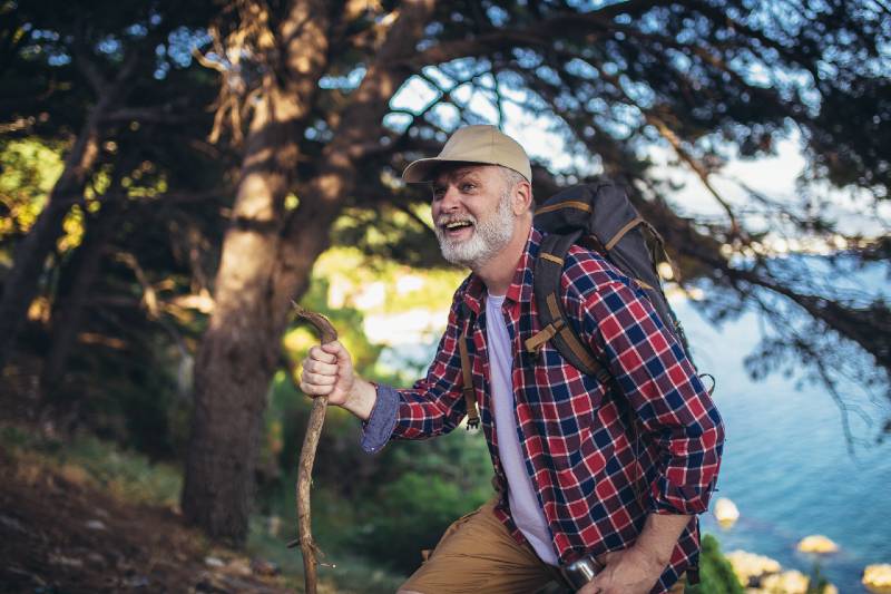 Mature man, hiking by the sea and exploring the nature-Camping With Seniors