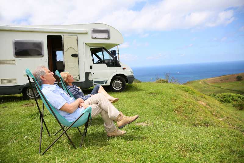 Senior couple relaxing in camping folding chairs, sea landscape-Camping With Seniors