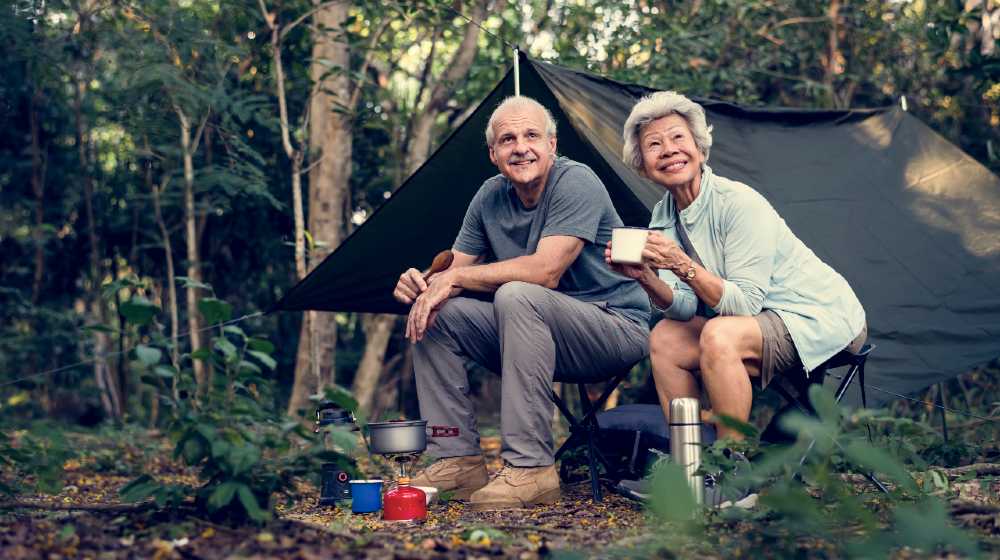 Senior friends having coffee at a campsite | 3 Useful Tips For Camping With Seniors | featured