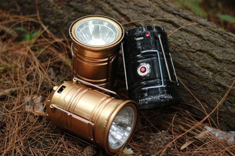 Solar cell tent flashlight against pine forest background.  a flashlight for lighting a tent when camping without electricity