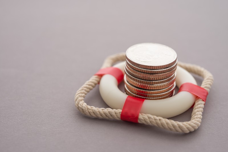 Stacked coins in red lifebuoy or lifebelt with gray background copy space. Assets wealth, money saving or money investment protection-prepping for shtf