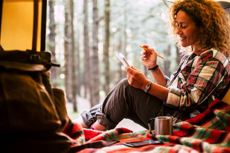 beautiful happy free woman in solo camping with tent in the forest write notes on notebook-Camping Alone