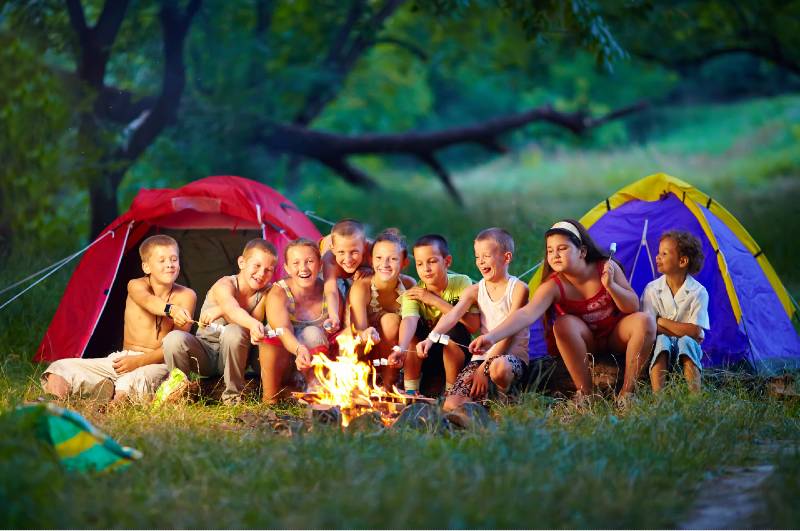 group of happy kids roasting marshmallows on campfire-Camping With A Large Group
