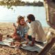 A young couple having a picnic at the beach | What To Bring To A Picnic | featured