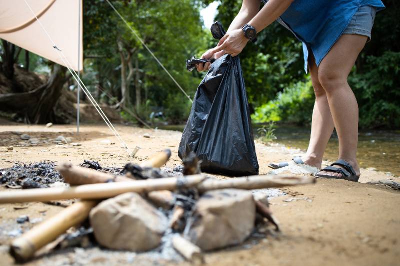 Asian people collecting litter with garbage bag at the national park,tourist pick up trash waste-car camping