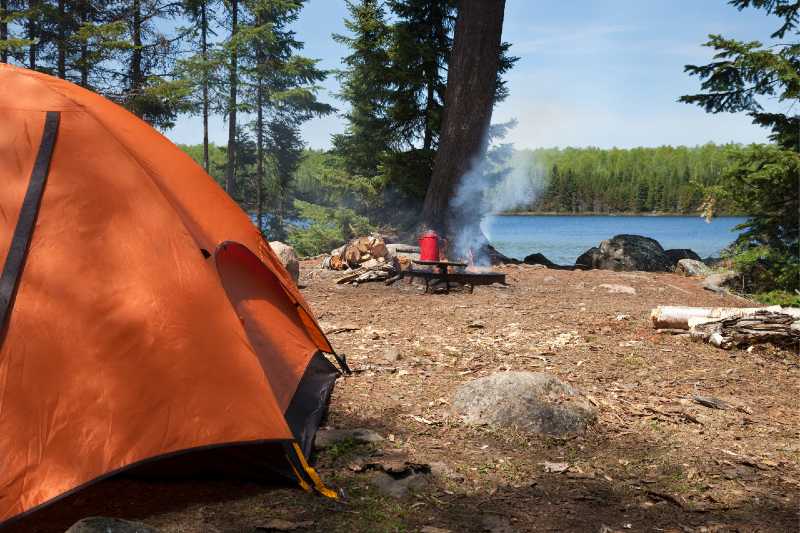 Campsite with orange tent and campfire on a northern Minnesota lake-How to Find A Good Campsite
