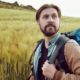 Half-turn portrait of bearded backpacker hiking in countryside admiring landscape | How to Pack a Hiking Bug Out Bag or Backpack | featured