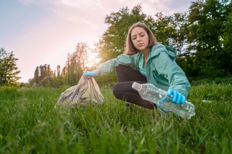 The girl collects garbage from the forest in the garbage bag - what to bring to the picnic