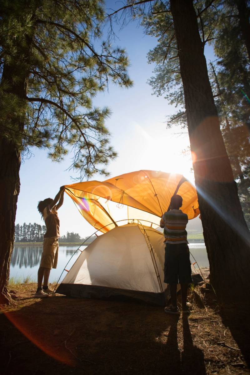 vertical-shot-father-son-assembling-orange camping tent 