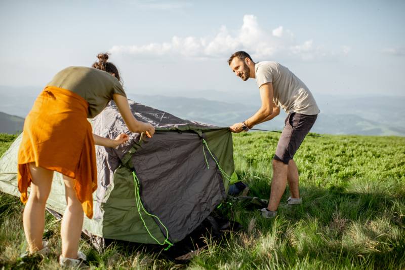young-couple-setting-tent-on-green camping tent 