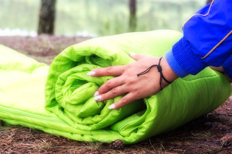 A woman folds and packs a sleeping bag-Truck Bed Tent