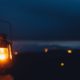 Blurred background image of a glowing lantern against dark night time mountains with lights | The Benefits of Having a Camping Lantern | featured