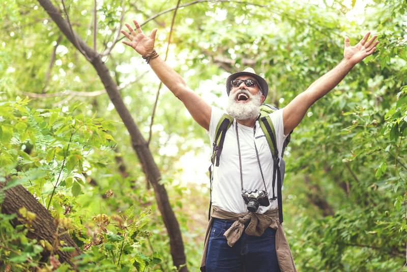 Happy old man feels freedom while traveling in forest hiking safety tips for active seniors