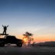 Hug the sky, view silhouette of a tourist standing on roof top of a 4WD-Truck Bed Camping
