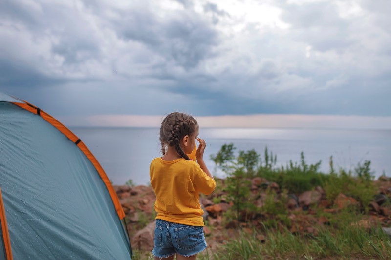 Child sits in the camping tent at the campsite |  Camping safety for children 
