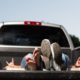 Young couple relaxing by laying down in the back of a pick up truck-Truck Bed Camping