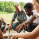 Young team is sitting by the campfire at a teambuilding workshop in nature | Where to Get the Best Survival Training | featured