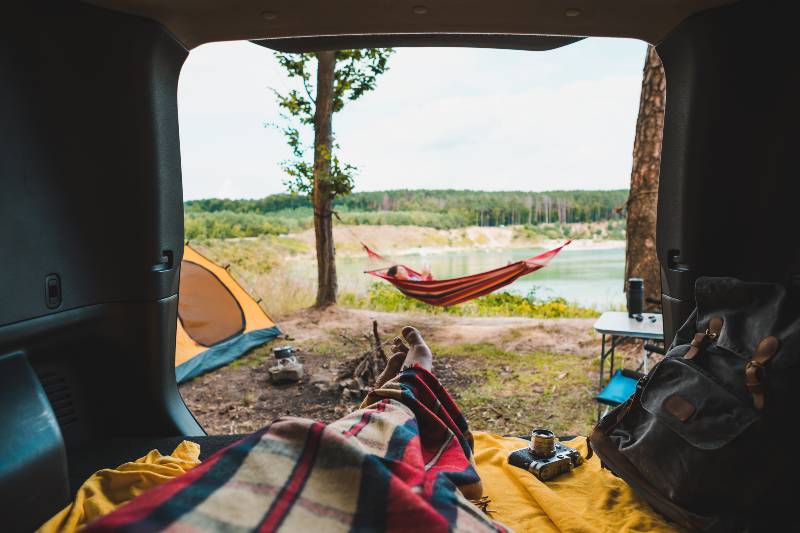 person view couple resting at camping woman laying in hammock with beautiful view of forest lake-Truck Bed Camping