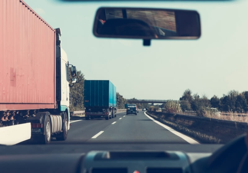 Blue and red freight truck on road | trucking news driver shortage