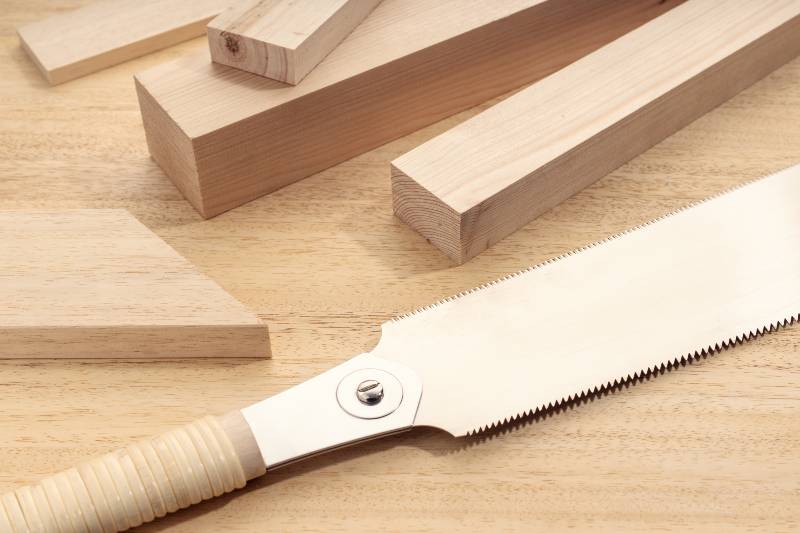 Groupe de différents matériaux en bois et une scie à main japonaise |  scie à main japonaise