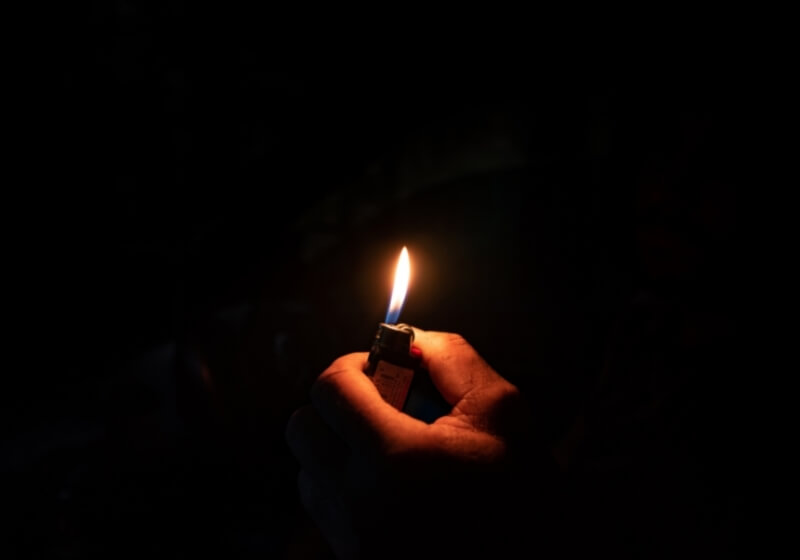 Hand lighting a lighter in the dark | How to Survive a Power Grid Attack