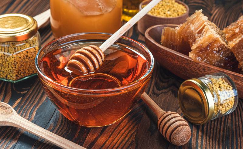 Honey in glass jar with honey dipper over wooden background with honeycomb-How to Make Mead