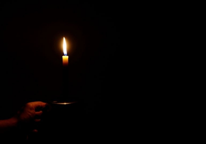 Man holding temporary lamp in dark blackout period | power grid cyber attack