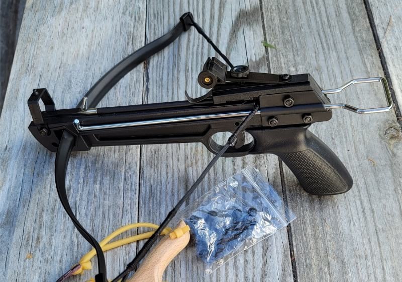 Slingshot and pistol crossbow on wood picnic table | Crossbow pistol