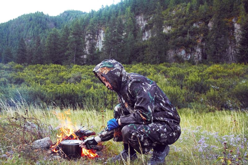 man-camouflage-preparing-food-on-campfire Survival Psychology 
