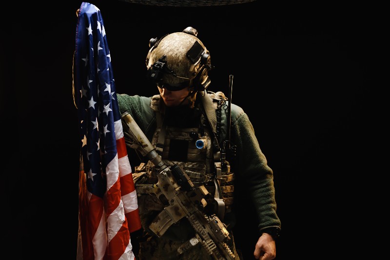 Special forces soldier holding US national flag in the dark-Physical Therapist