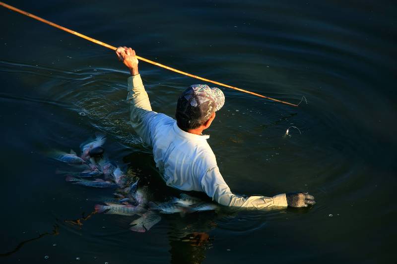 man fishes with a spear in a lake-primitive fishing